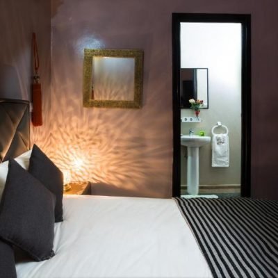 Cozy traditional Moroccan suite with ornate decor and comfortable bedding at Riad Dar Benbrahim